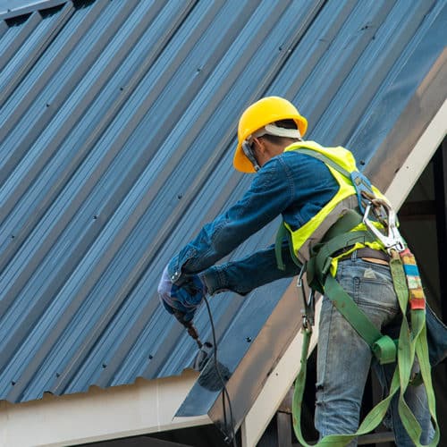 contractor-with-protection-equipment-installing-metal-roof-at-property-with-drill-longview-tx