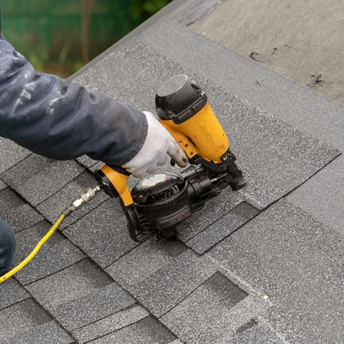 roofer-arm-close-up-with-nailgun-installing-asphalt-shingles-roof-replacement-longview-tx