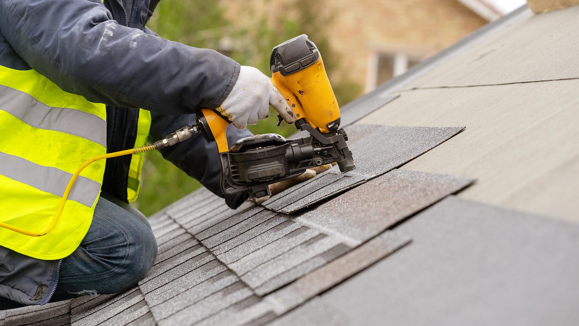 roofer-close-up-with-protection-equipment-and-nailgun-installing-asphalt-shingles-roof-longview-tx