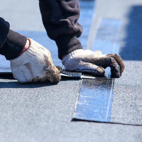 roofer-hand-with-gloves-close-up-installing-flat-roof-at-commercial-property-longview-tx